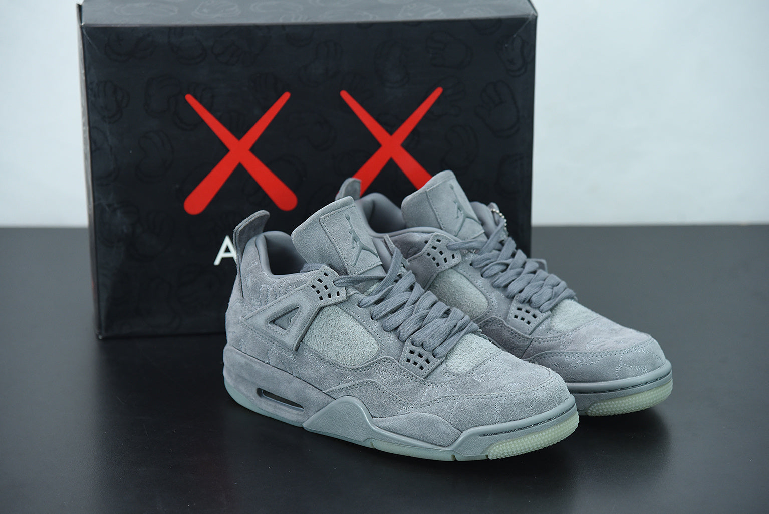 Gray sneakers with a black box featuring red 'X' marks on a gray surface.