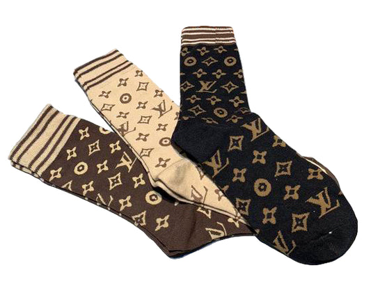 Three pairs of socks with a pattern in front of a Supreme box.