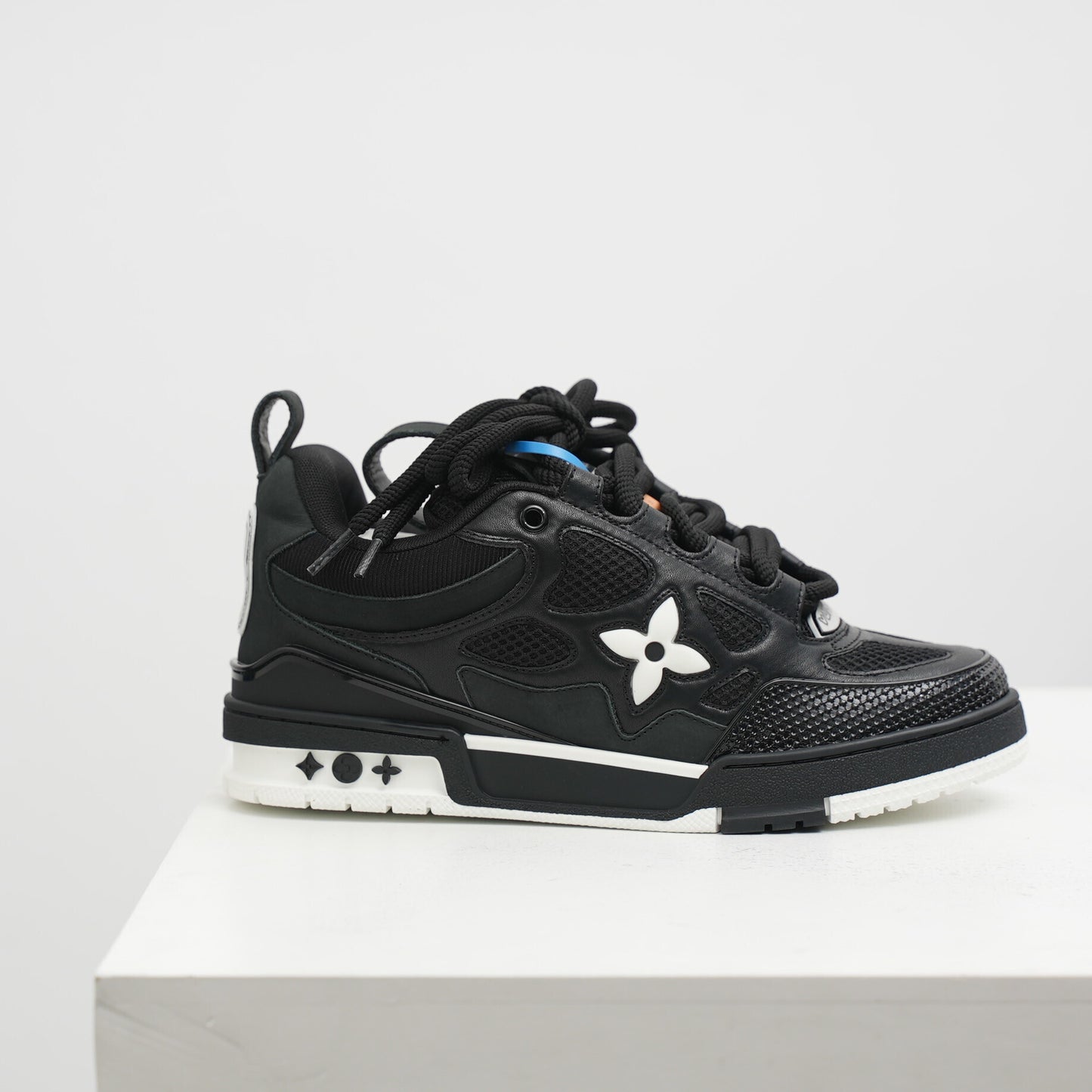 lv Black sneaker with a white flower design on a light gray background