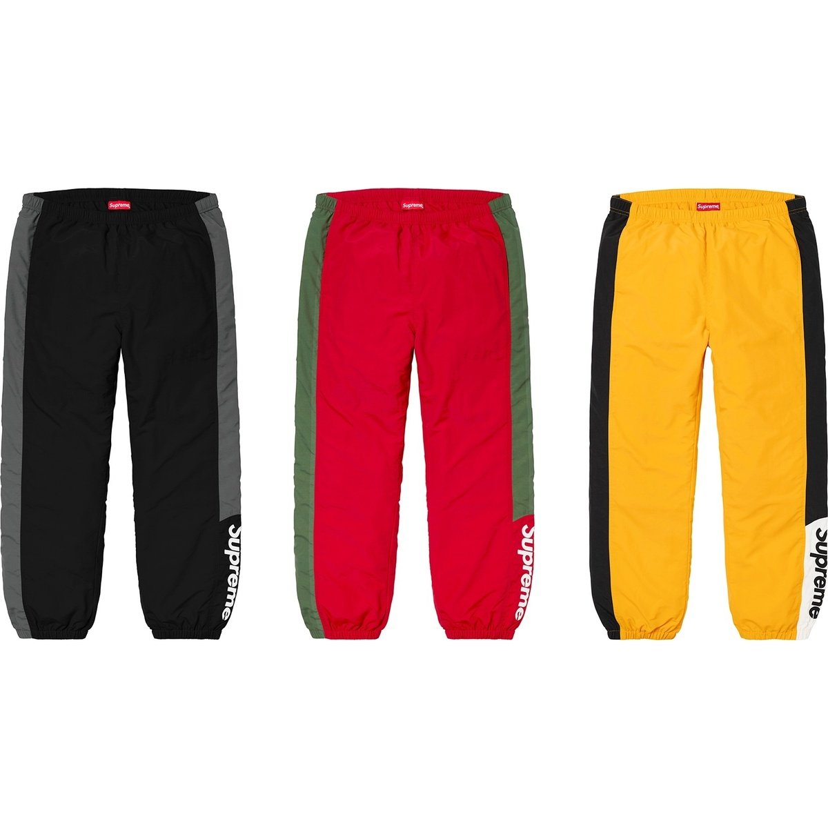 3 pairs of supreme track pants in colors black, red, and yellow 