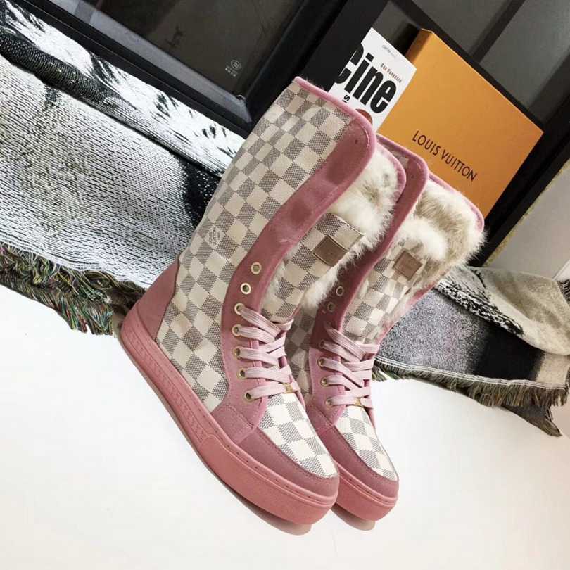 A pair of pink with white checkered, Louis Vuitton , high top boots, with white fur, on a white platform 