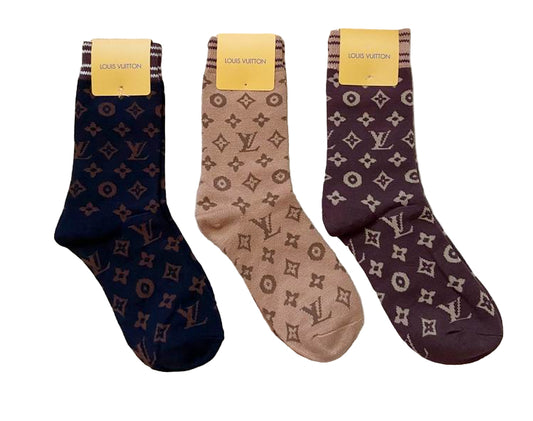 Three pairs of Louis Vuitton socks with packaging on a textured surface.
