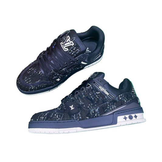Navy blue sneakers with white soles on a green surface, next to an orange box.