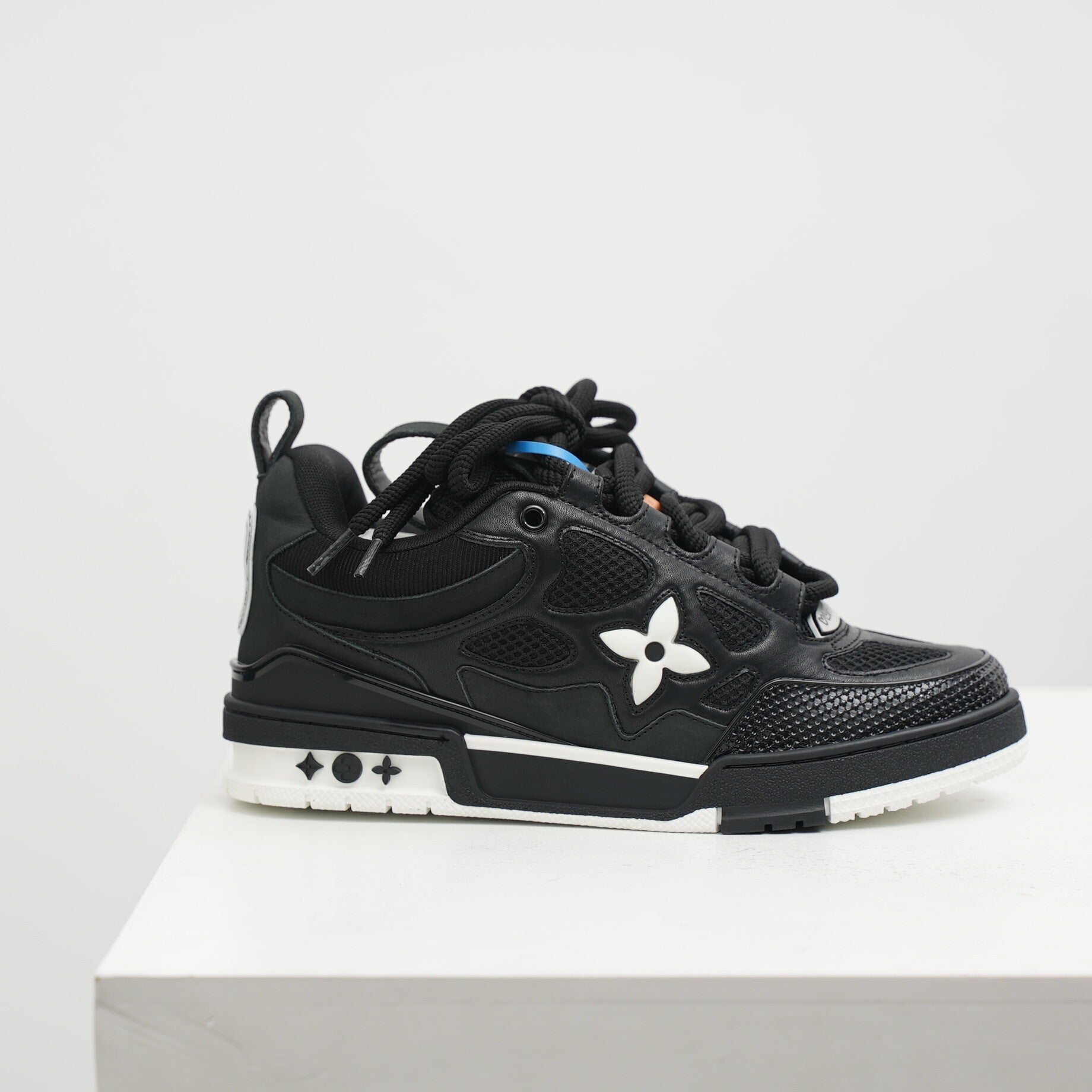 lv Black sneaker with a white flower design on a light gray background