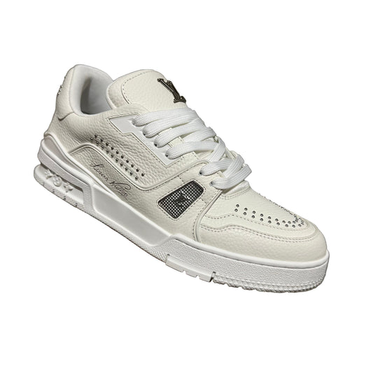 lv White sneaker held by a hand against a textured gray background