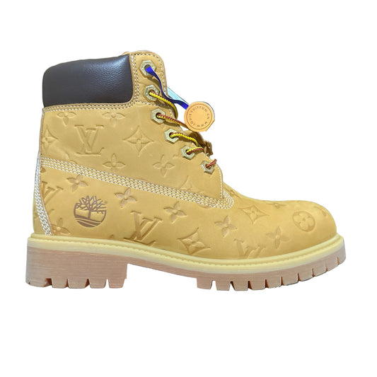Yellow boot with brand logo held by a hand on a dark textured background